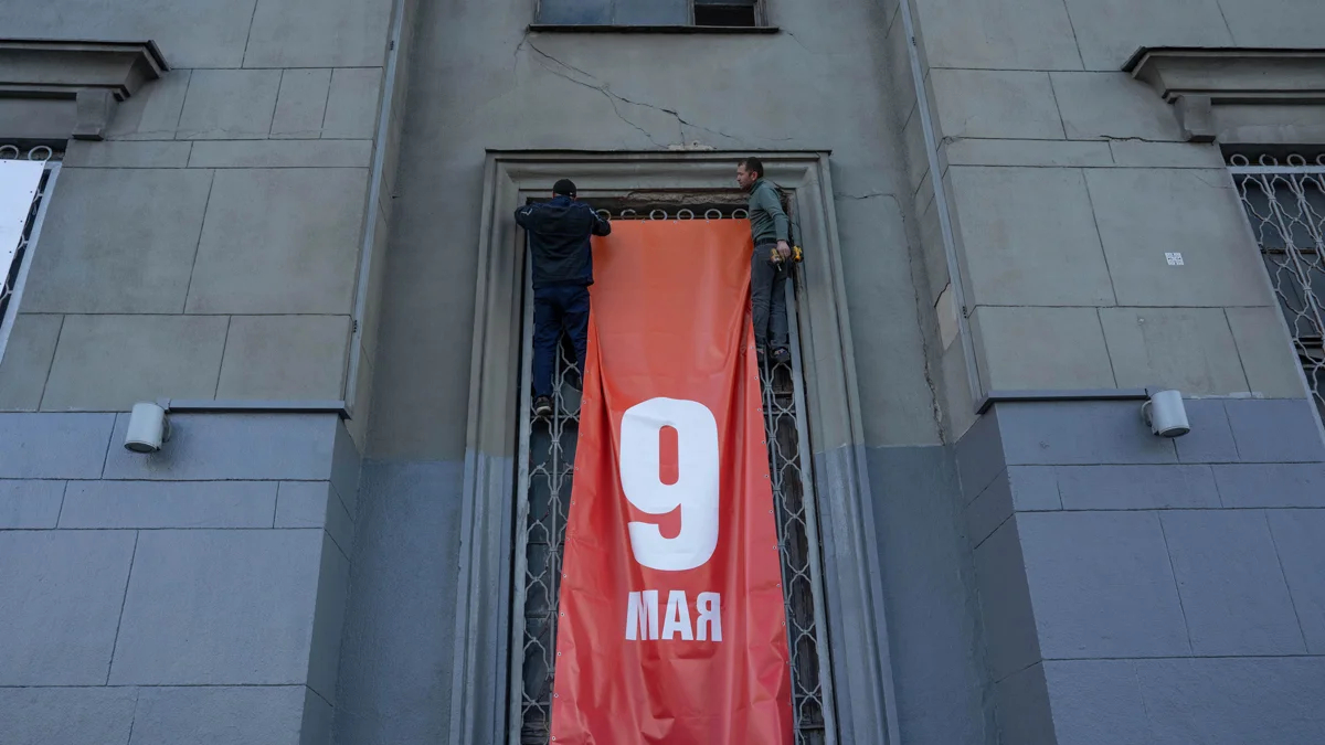 Рабочие устанавливают огромный баннер на заброшенном доме на Ленинградском проспекте. Накануне его частично оштукатурили и выкрасили свежей серой краской.